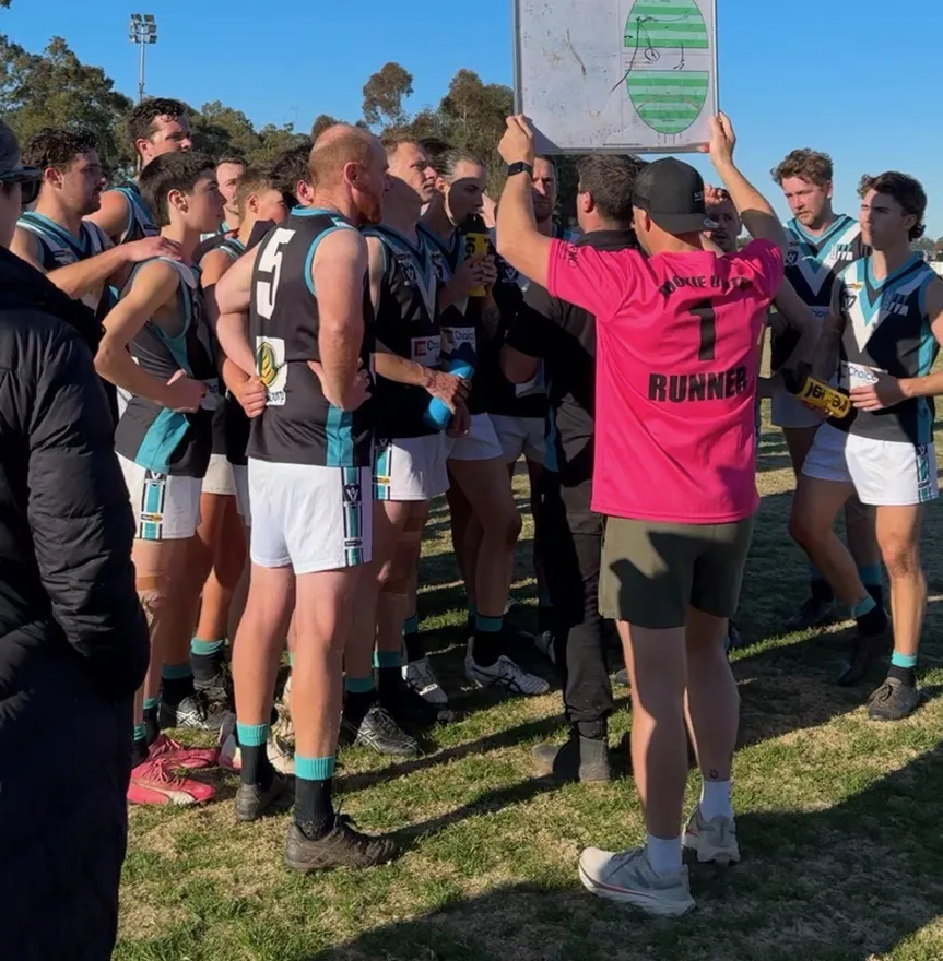 Dookie United senior football coach holding up a whiteboard to brief the team during a break in play