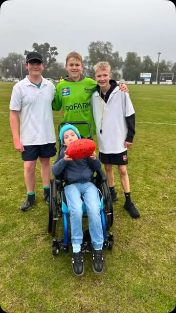 Junior players including a teammate in a wheelchair, together on the oval at Dookie United